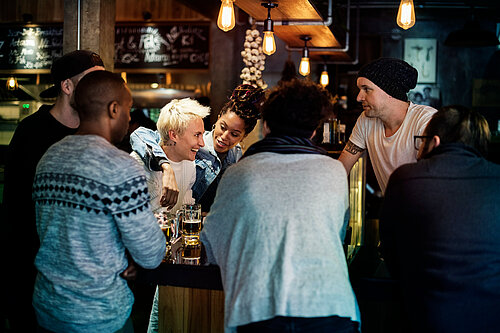 6 people smiling and drinking at a bar